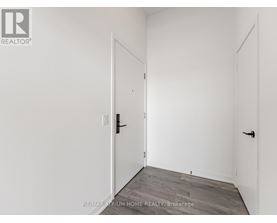 A white room with a door and a brokerage sign.