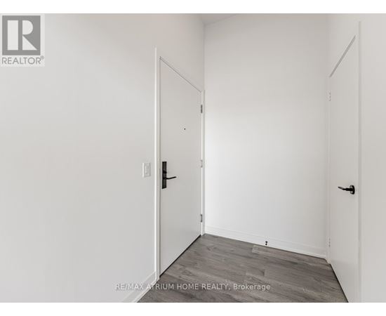A white room with a door and a brokerage sign.