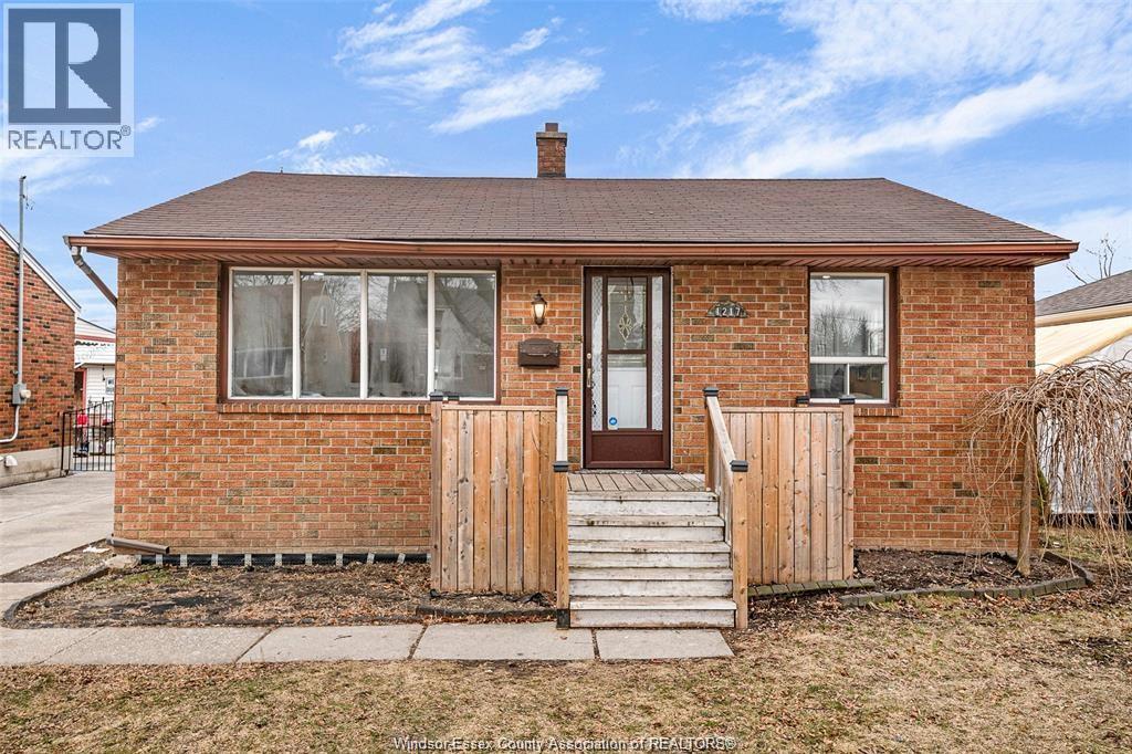 A small brick house with a brown door and a small porch.