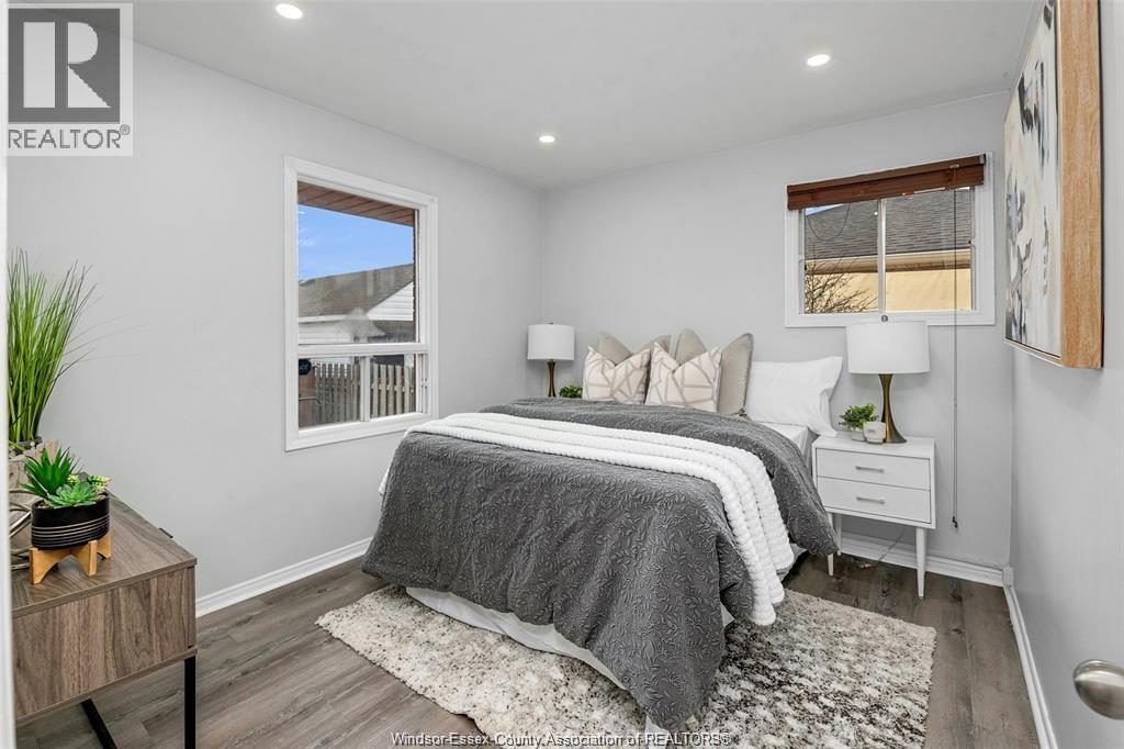 A bedroom with a large bed and a window overlooking a fence.