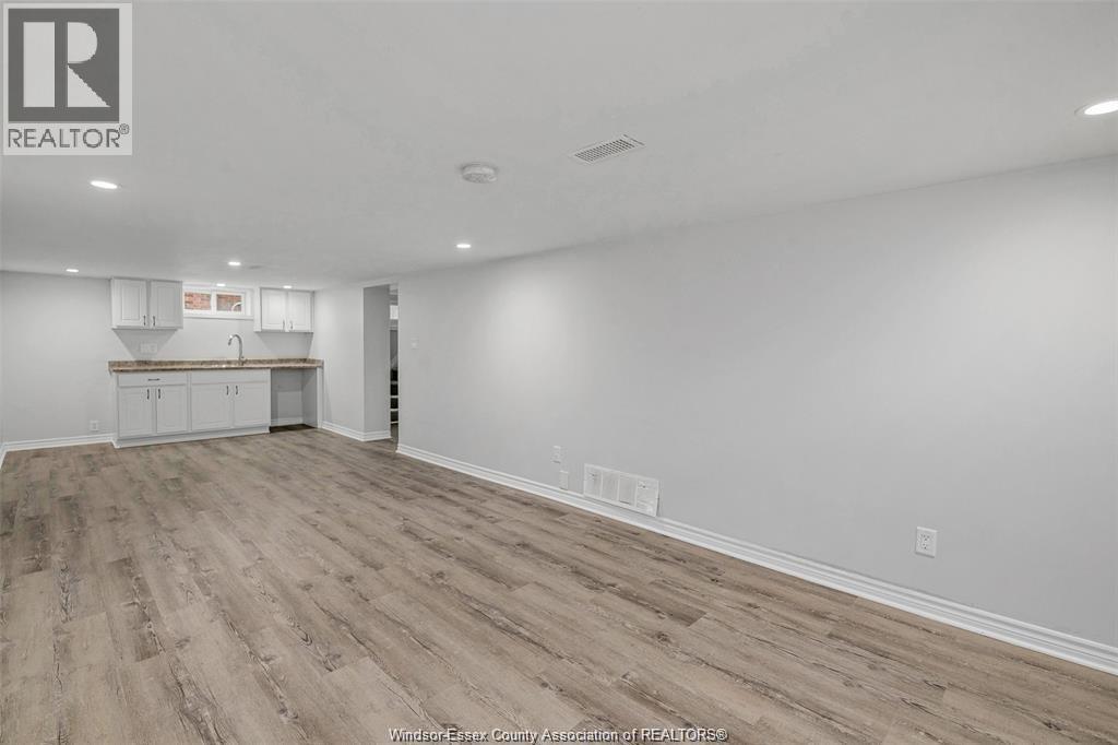 A spacious room with wooden flooring and white walls.