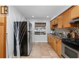A kitchen with wooden cabinets and a black refrigerator.