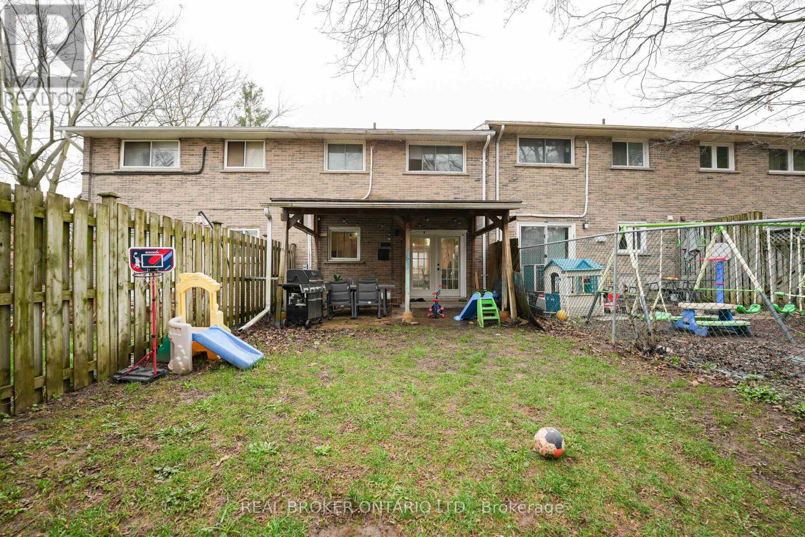 A backyard with a wooden fence and a ball on the grass.