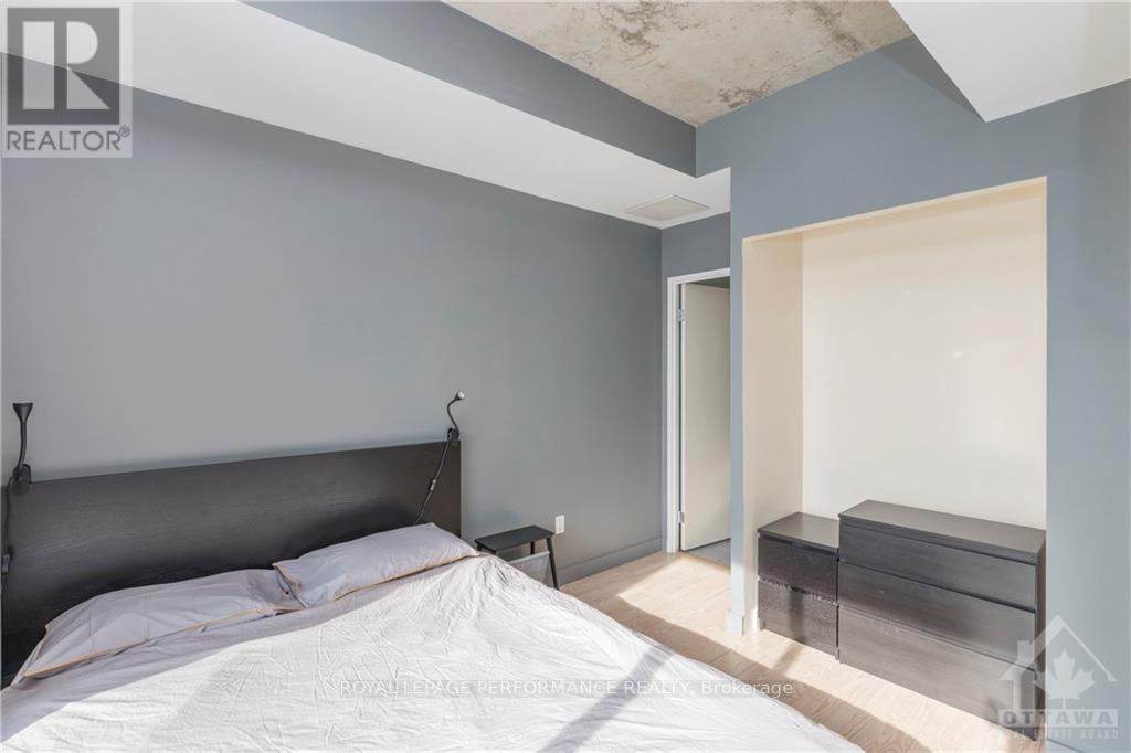 A bedroom with a bed, nightstand, and a bench in the corner.