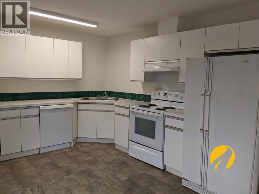 A kitchen with white cabinets and a white refrigerator with a yellow logo on it.