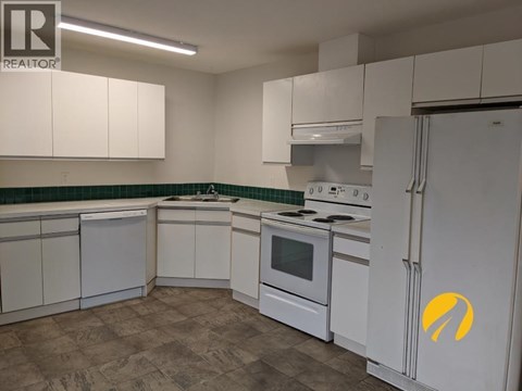 A kitchen with white cabinets and a white refrigerator with a yellow logo on it.