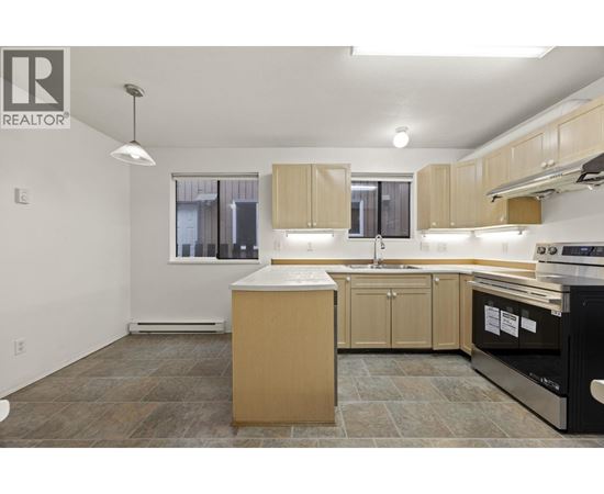 A kitchen with a black oven and wooden cabinets.
