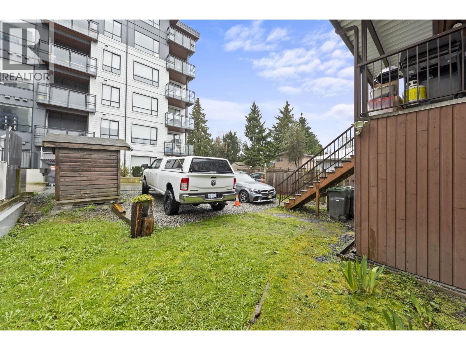 A white car is parked in a grassy area in front of a building.