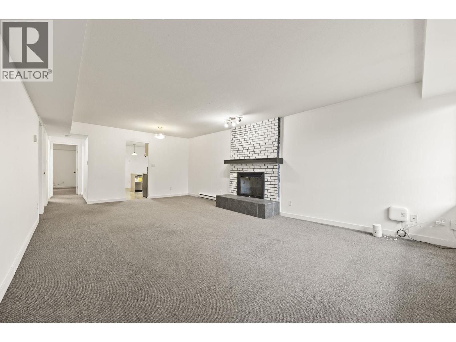 A spacious living room with a fireplace and a carpeted floor.