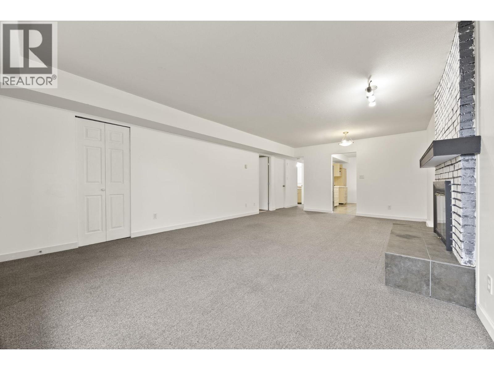 A spacious room with a fireplace and a carpeted floor.