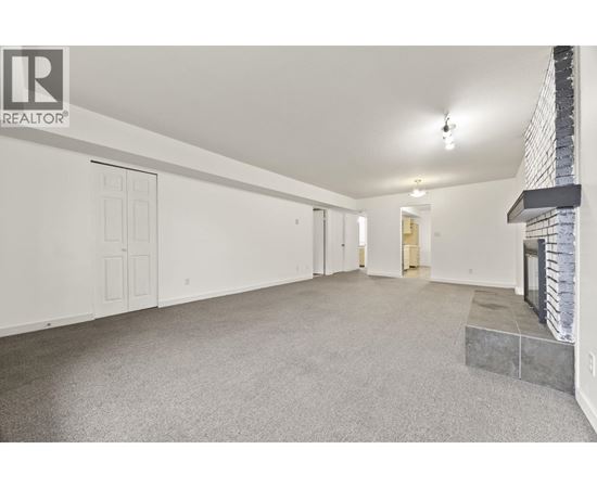 A spacious room with a fireplace and a carpeted floor.