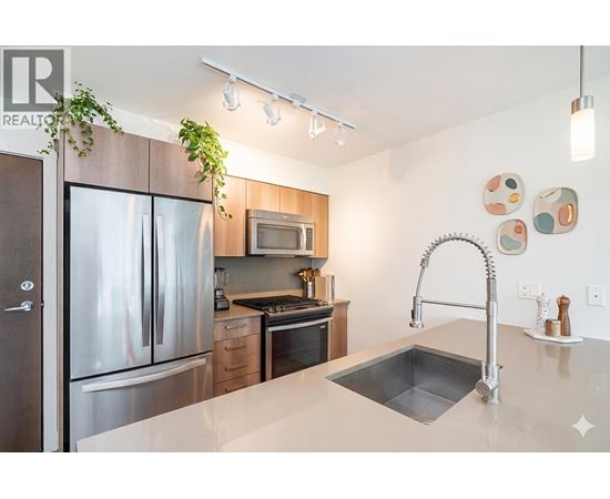 A modern kitchen with a stainless steel refrigerator and a sink.