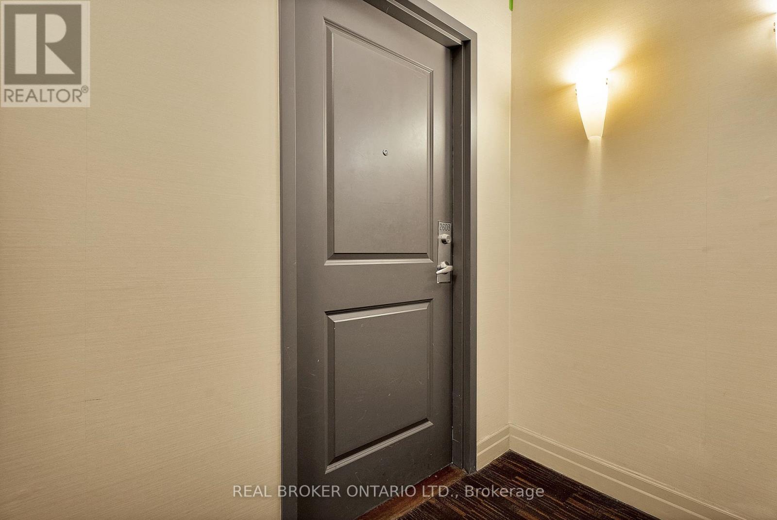 A grey door in a hallway with a Real Broker Ontario Ltd. logo on the wall.