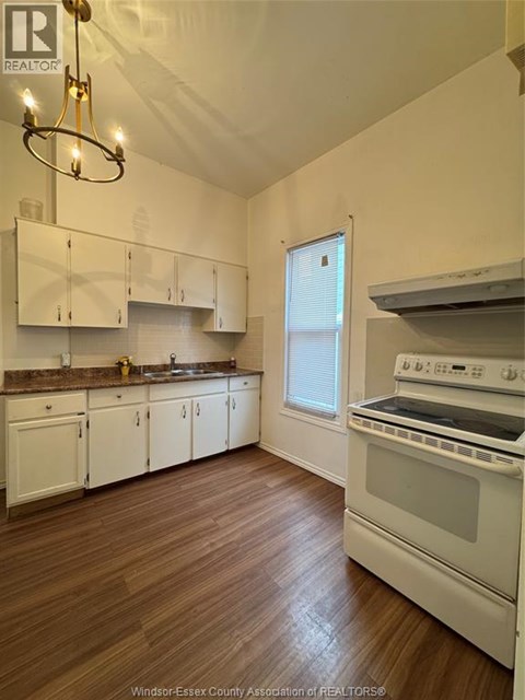 A kitchen with white cabinets and a wood floor.