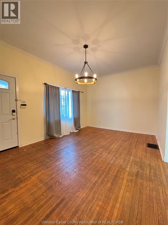 A room with wooden flooring and a hanging light fixture.