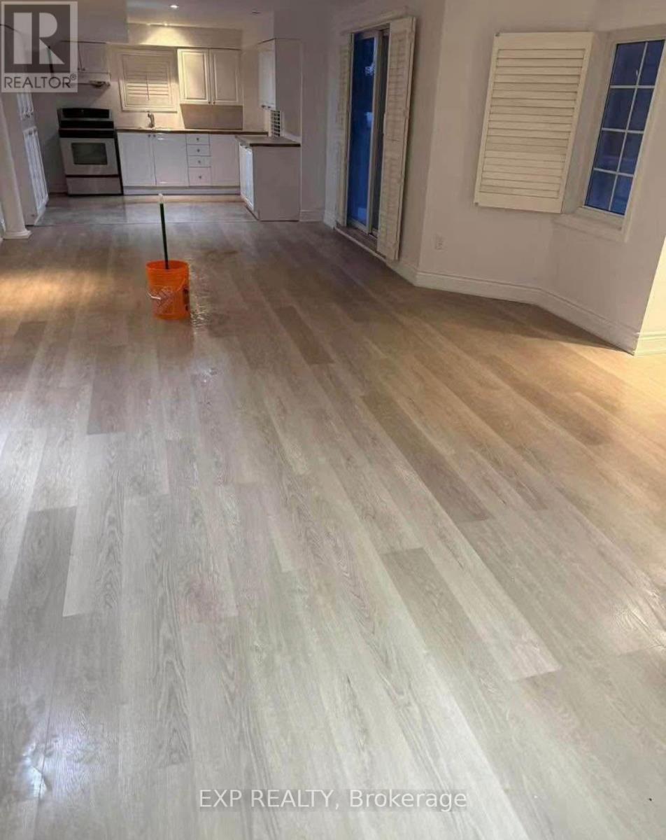 A room with wooden flooring and a brokerage sign.