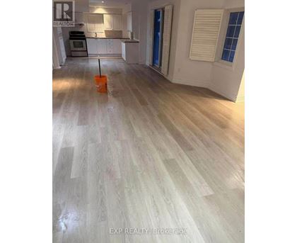 A room with wooden flooring and a brokerage sign.