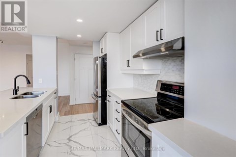 A modern kitchen with white cabinets and a black stove top oven.