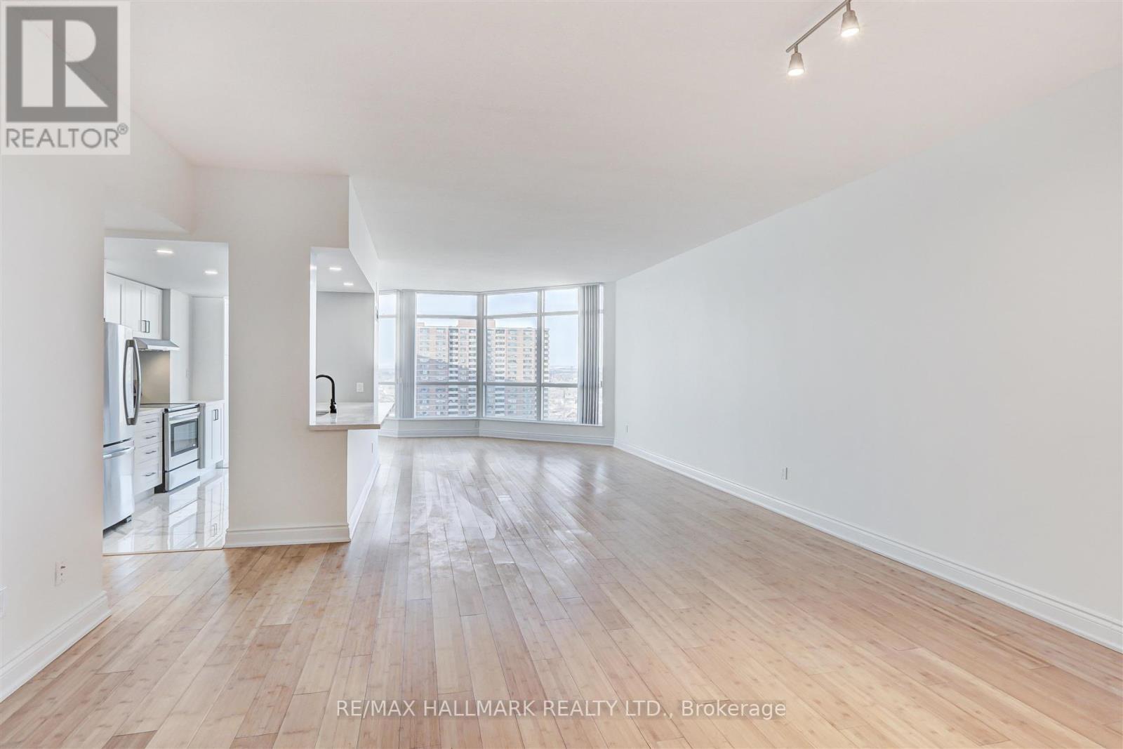 A spacious, empty room with wooden flooring and white walls.