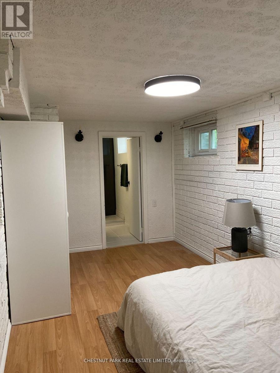 A bedroom with a bed, lamp, and white brick wall.