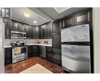 A modern kitchen with black cabinets and stainless steel appliances.
