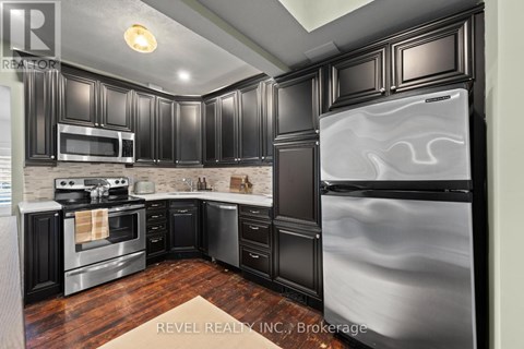 A modern kitchen with black cabinets and stainless steel appliances.
