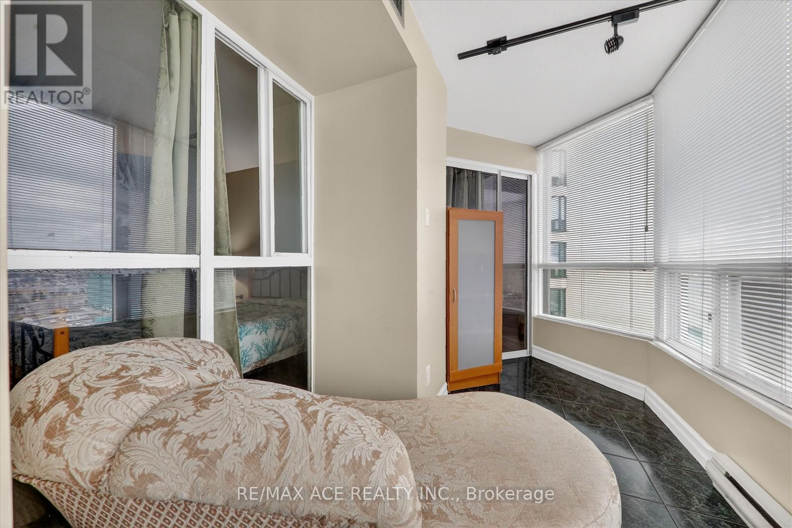 A bedroom with a bed, a window with blinds, and a sliding glass door.