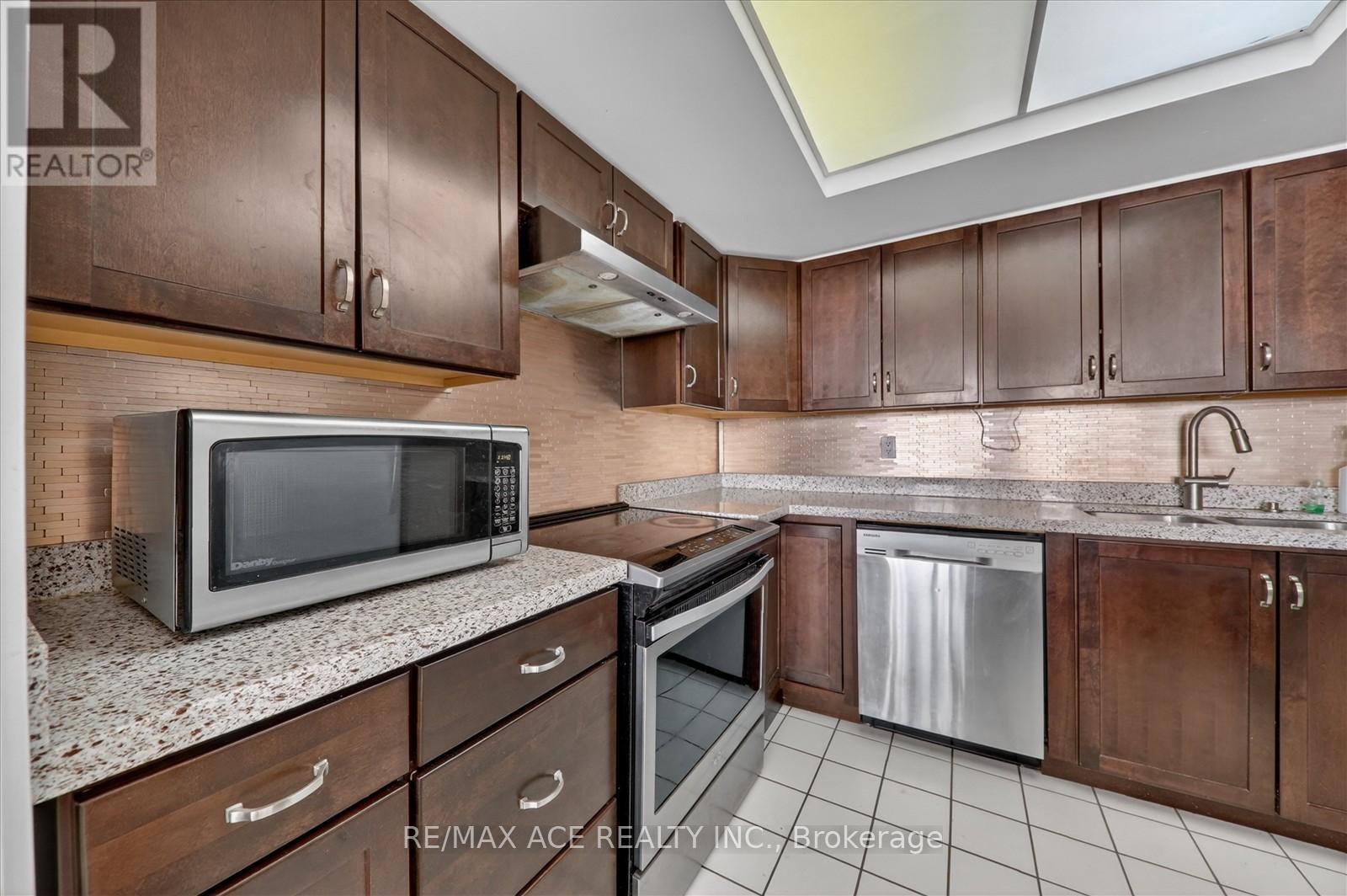 A kitchen with brown cabinets and a white microwave.