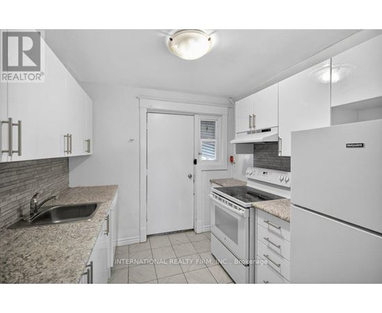A white kitchen with a sink and a refrigerator.