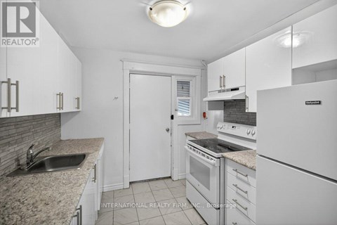 A white kitchen with a sink and a refrigerator.
