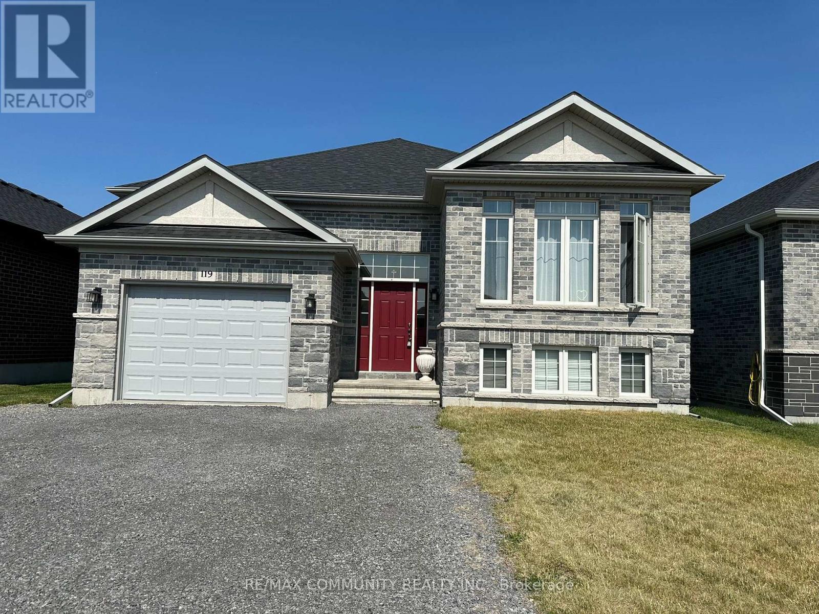 A house with a red door and a garage door is for sale.