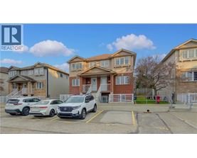 A row of houses with cars parked in front.