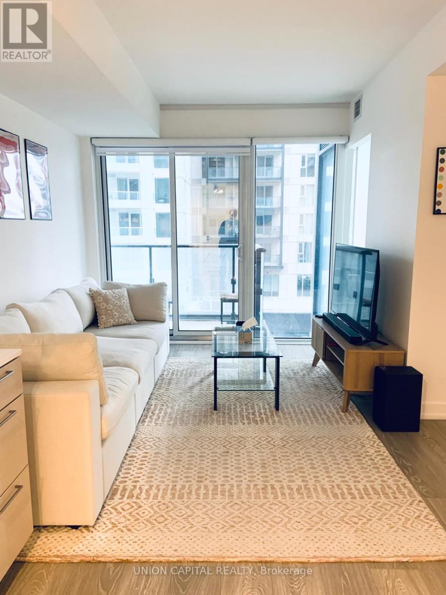 A living room with a white couch and a glass coffee table.
