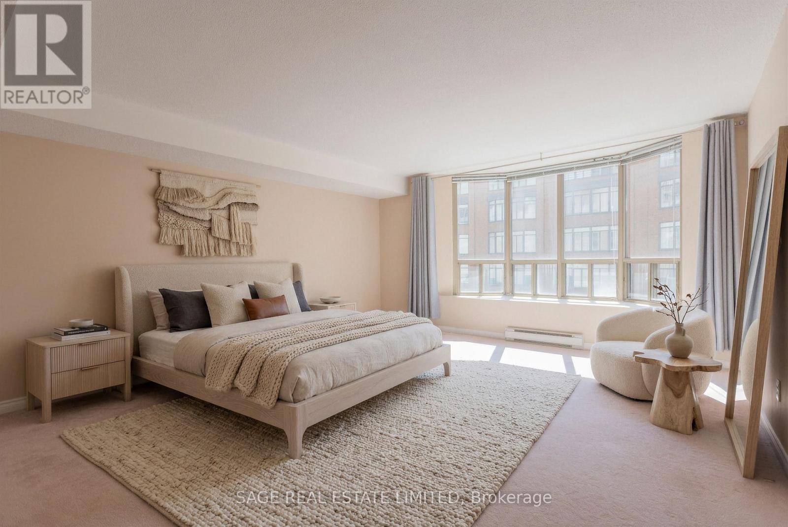 A bedroom with a large bed and a window with curtains.
