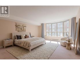 A bedroom with a large bed and a window with curtains.