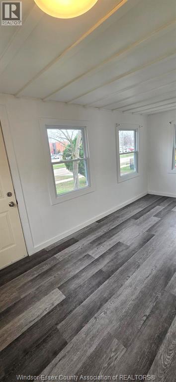 A room with a grey floor and two windows.