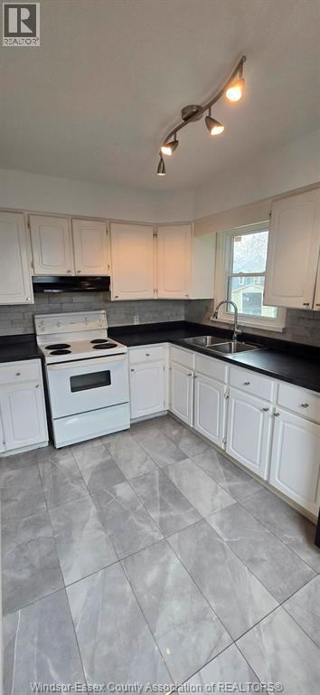 A kitchen with white cabinets and a black countertop.