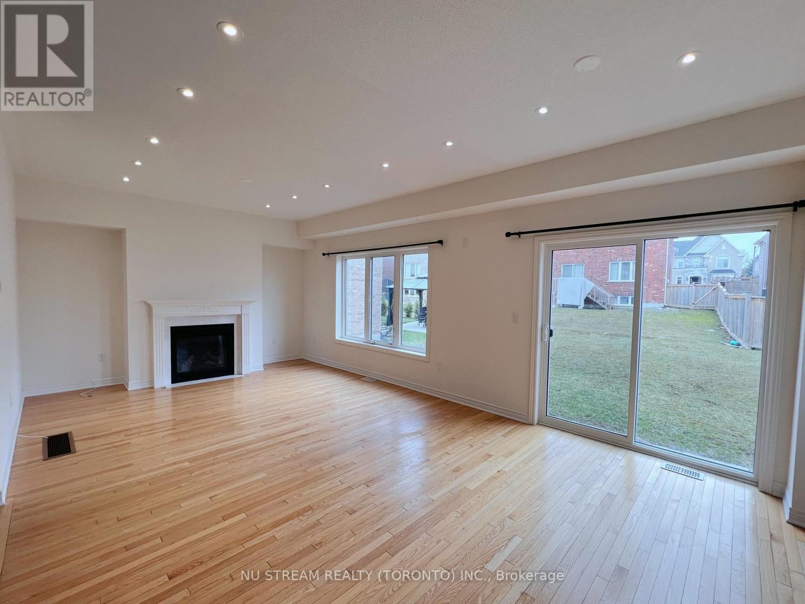 A spacious room with wooden flooring and a fireplace.