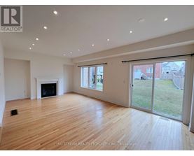 A spacious room with wooden flooring and a fireplace.