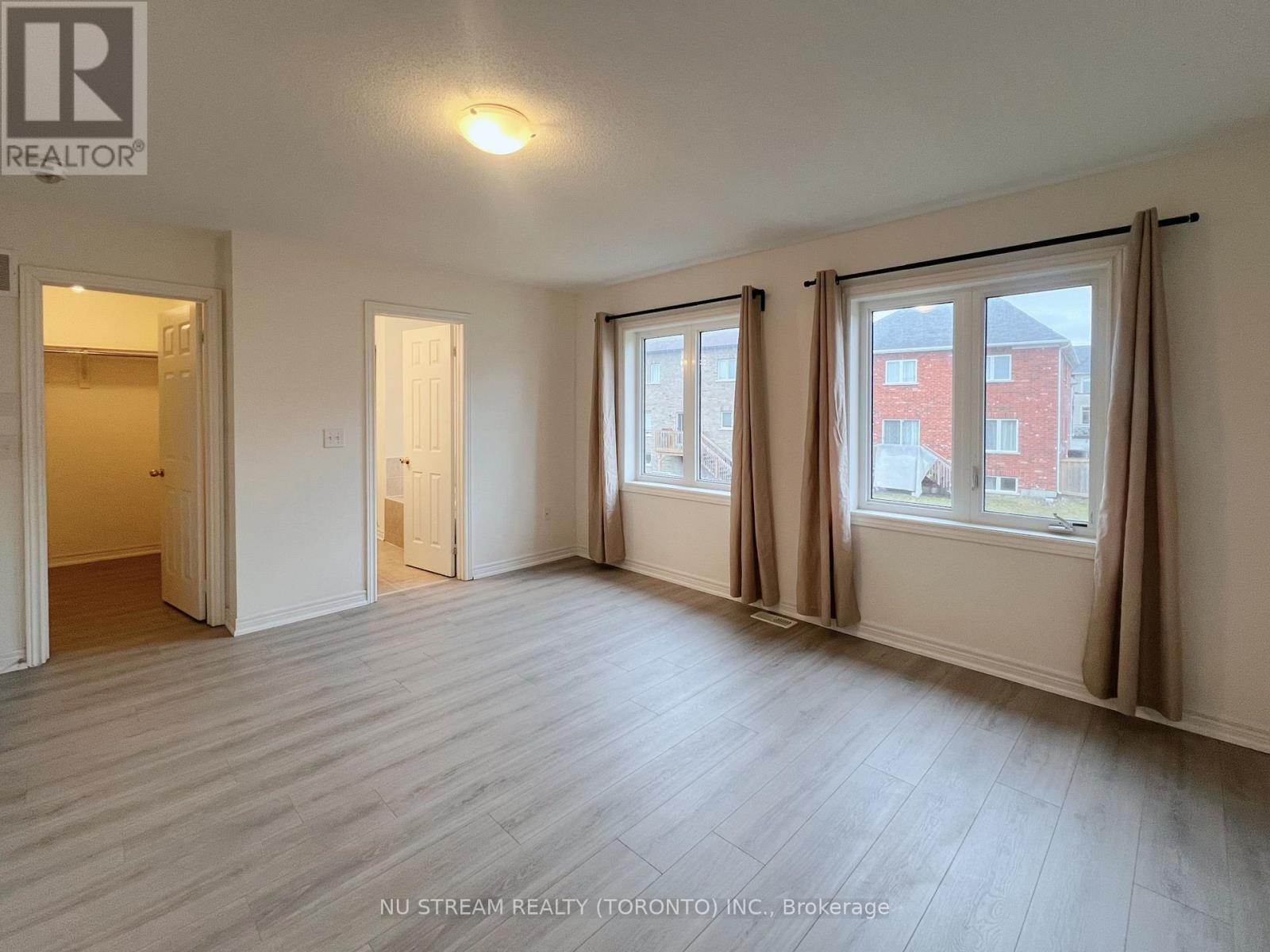 A room with a large window and a door leading to another room.