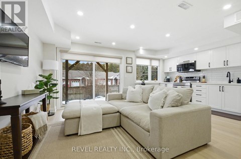 A modern living room with a large sectional sofa and a flat screen TV mounted on the wall.