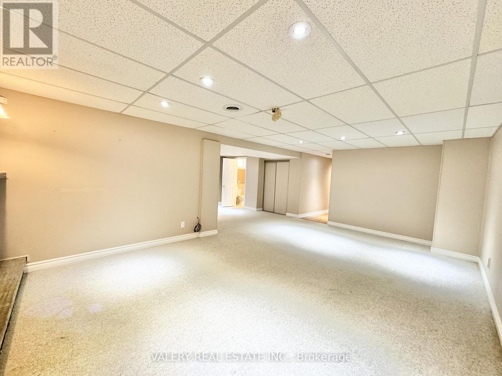 A spacious room with a carpeted floor and a doorway leading to another room.