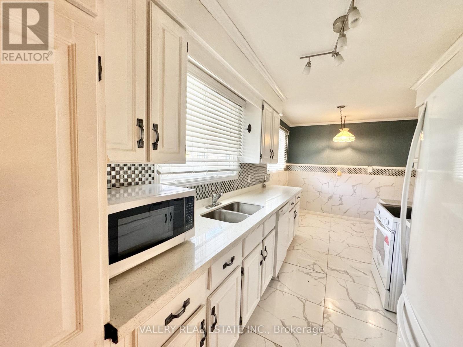 A kitchen with white cabinets and a black and white checkered backsplash.