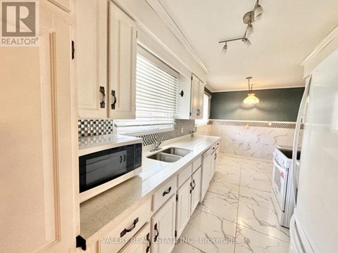 A kitchen with white cabinets and a black and white checkered backsplash.