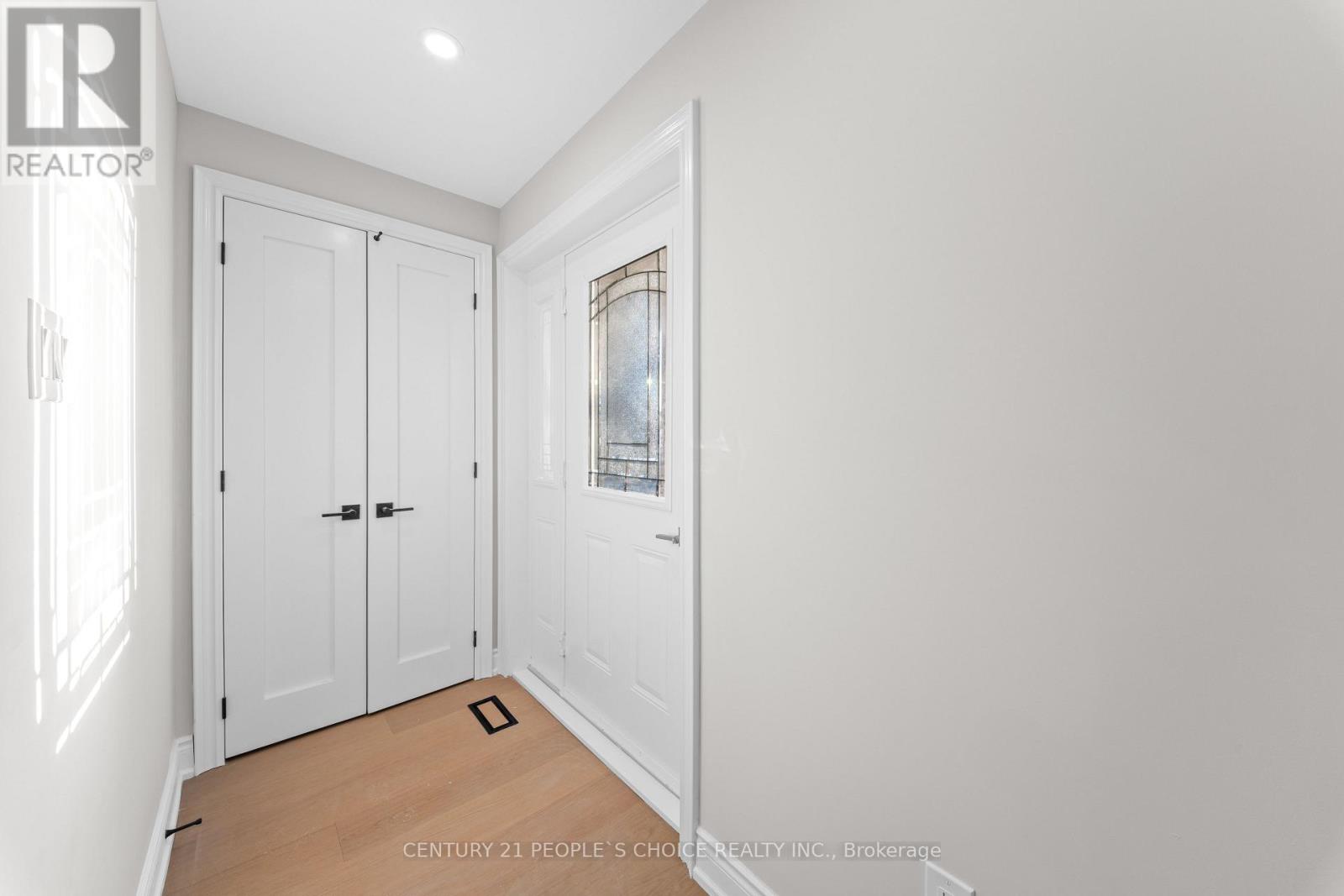 A white bedroom with a wooden floor and a window with bars.