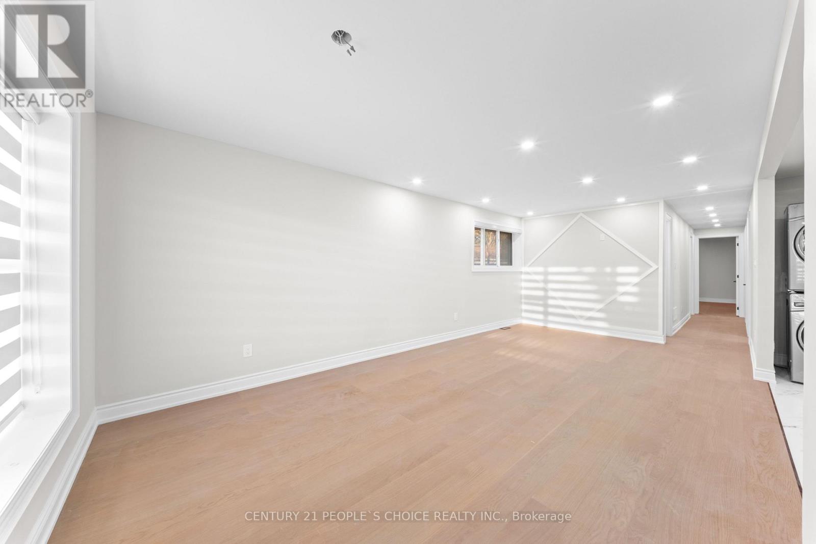 A spacious room with wooden flooring and white walls.