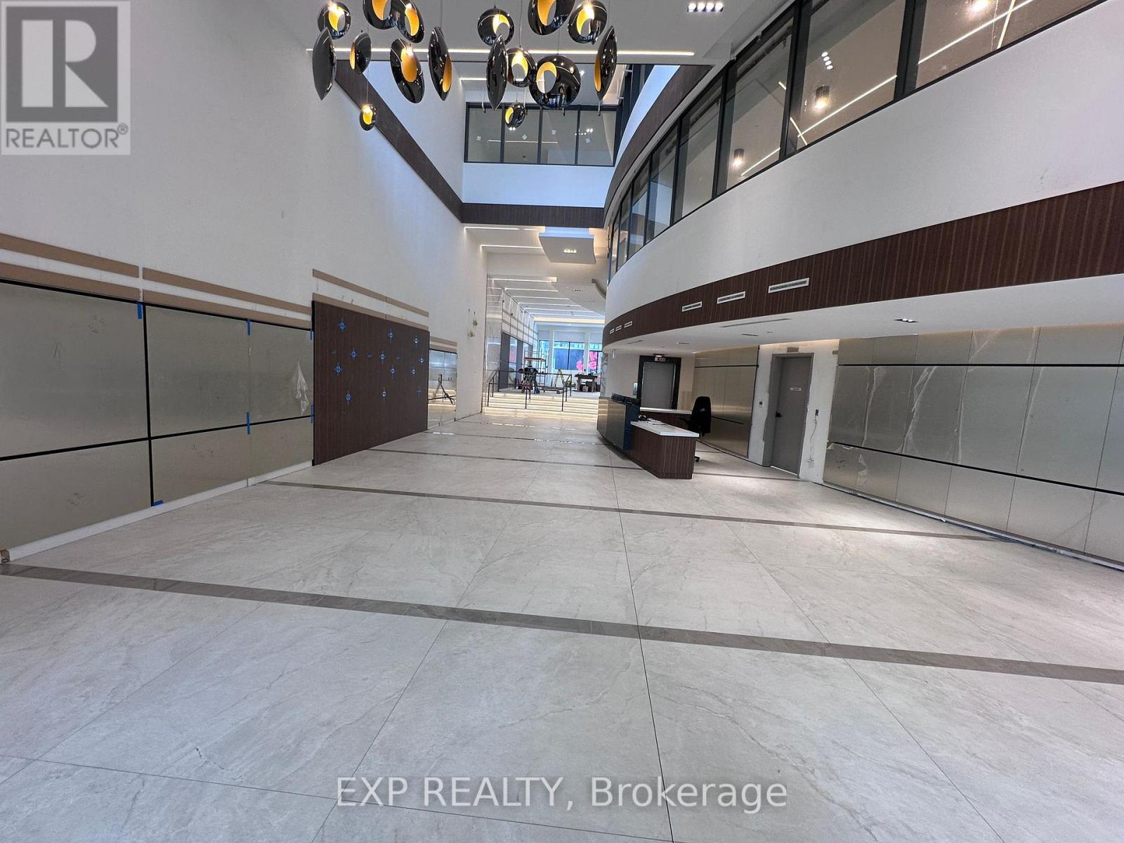 A spacious interior with a long hallway, glass walls, and a lighting fixture.
