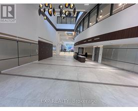A spacious interior with a long hallway, glass walls, and a lighting fixture.