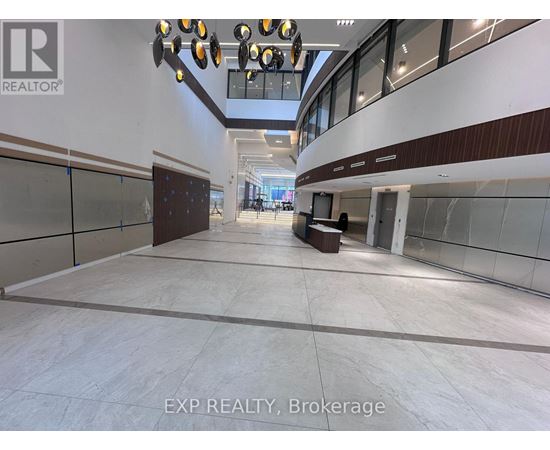 A spacious interior with a long hallway, glass walls, and a lighting fixture.