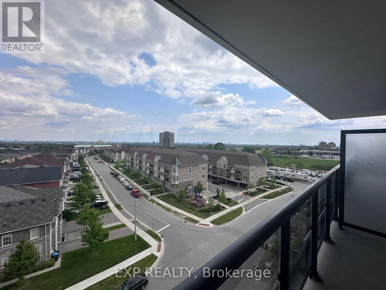 A view from a balcony looking out at a street lined with houses and cars.